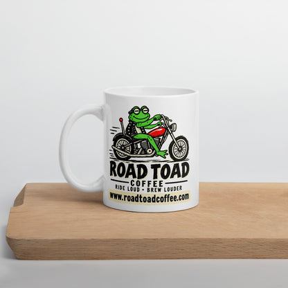 White 11 oz Road Toad Coffee mug with the toad on a motorcycle and roadtoadcoffee.com, on a cutting board
